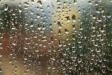 Rain drops on window with house and church in background