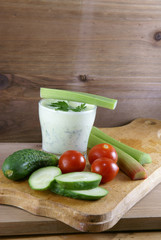 Useful summer snack: vegetables and yogurt sauce with herbs. Against the background of a rustic wooden table