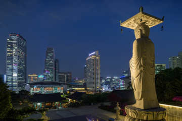 Obraz premium Mireuk Daebul statue (The Great Statue of Maitreya Buddha) at the Bongeunsa Temple and view of Gangnam in Seoul, South Korea at night.