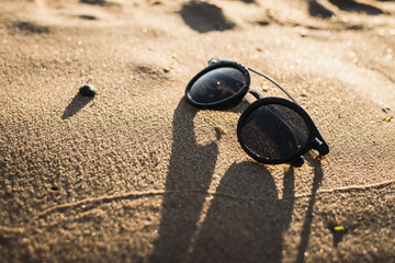 Stylish black retro glasses in the sand at the beach. Isolated.