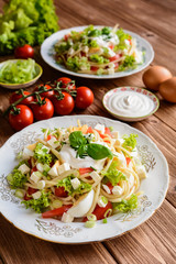 Spaghetti pasta salad with tomato, lettuce, egg, Feta cheese, green onion and sour cream