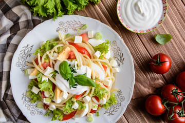 Spaghetti pasta salad with tomato, lettuce, egg, Feta cheese, green onion and sour cream