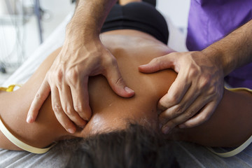 Fototapeta na wymiar Fisioterapeuta trabajando los hombros de una joven deportista. Quiromasajista terapéutico trabajando. Tratamiento de sobrecarga muscular.