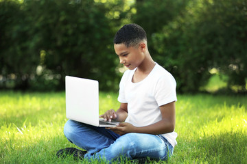 African American boy with laptop in park