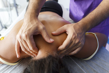 Fisioterapeuta trabajando los hombros de una joven deportista. Quiromasajista terap&eacute;utico trabajando. Tratamiento de sobrecarga muscular.