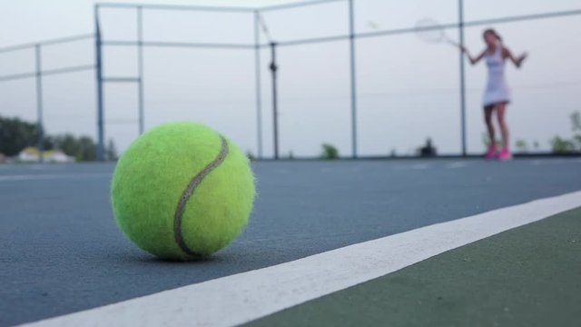 Yellow tennis ball and net on a green court. Slow motion