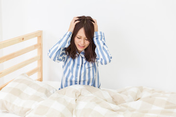 パジャマを着た女性　ベッド　不機嫌