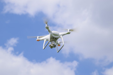 Flight quadrocopters white against the blue sky with clouds