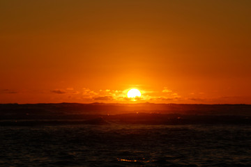 Obraz premium Sunset into the ocean through the clouds and reflecting on the P