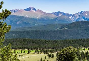 view of  the  meadows and foot hills  below the snow dotted  peaks of the Rocky Mountains in Colorado
