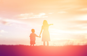 Fototapeta premium Mother encouraged her son outdoors at sunset, silhouette concept