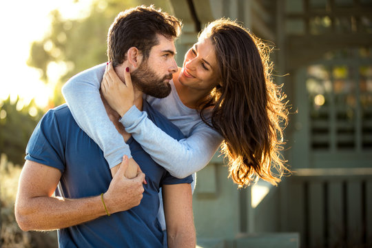 Handsome bearded man and brunette woman strong athletic lovers embrace at the park