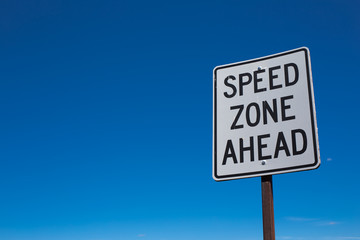 White speed zone limit sign with blue sky background