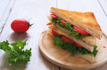 Close up ham and cheese sandwiches on a wooden plate.