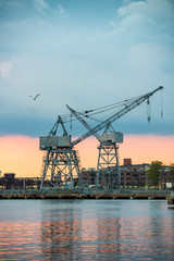 View of the city industrial area with port cranes at sunset time..