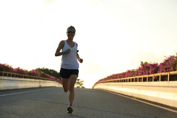 young woman runner running on city bridge road