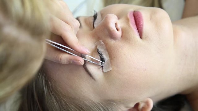 Beautiful young woman with eyelash extension. Woman eye with long eyelashes. Beautician eyelash extension for young woman in a beauty salon