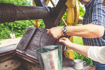 male and female hand pull bucket out of well © glebchik