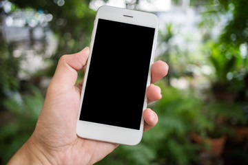Man's hand shows mobile smartphone, blurred garden background