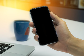 Close up of a man using smart phone with blank mobile and cup of