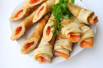 Appetizing snack pancakes with red caviar and greens on a white plate