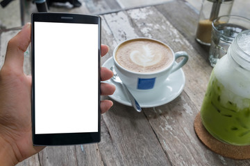 Close up of a man using smart phone with blank mobile and cup of