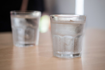 glass of water on a wooden table in a restaurant.selective focus