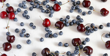 Fresh cherries and blueberryon a cloth from flax, top view. Berry mix.