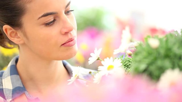 springtime smiling woman smells the daisies in flowers garden