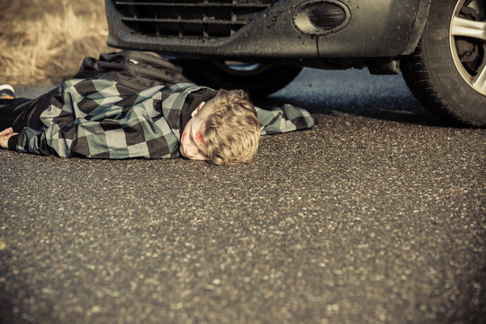 Teen Boy Car Accident Victim Lying On Road By Car