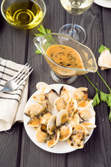 Pacific clams cooked in sauce and sauceboat on wooden