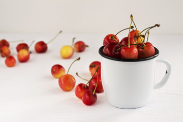 Sweet cherries in white enamel mug