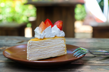 Piece of crepe cake on plate with strawberries.