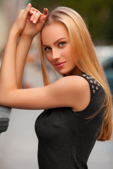 Obraz premium Beautiful sexy woman with black dress and blond hair posing outdoor. Fashion girl portrait