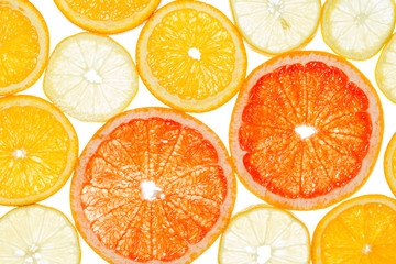 Lemon, grapefruit and orange cut by segments located close photographed against the light isolated on white background