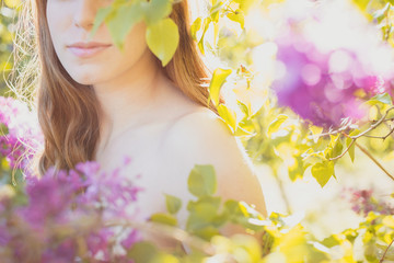 Sexy sensual female shoulders and lips on a background of a blossoming spring garden.