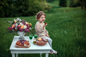 Little baby girl eats chocolate cake in nature at a picnic. The concept of a happy childhood