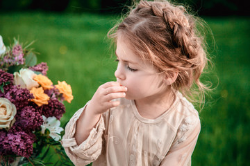 Little baby girl eats chocolate cake in nature at a picnic. The concept of a happy childhood
