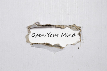 The word open your mind appearing behind torn paper