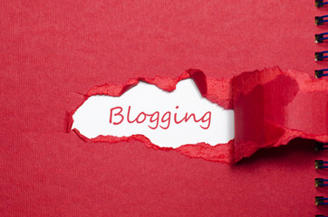 The word blogging appearing behind torn paper
