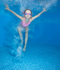 Small girl jumps and having fun in water. 