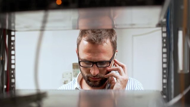 Engineer working in data room, speaking on phone. Slow motion.