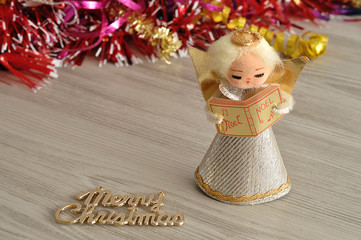 An angel to decorate a Christmas tree with tinsel in the background