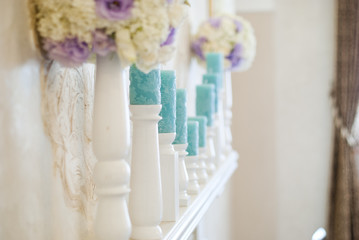Floral arrangement with white and blue flowers and candles on candle holders. Wedding decor idea. 
