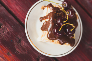 piece of cake with chocolate icing and cherries, puff pastry Napoleon  on a white plate,