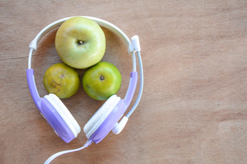 Apple and headphones on the wooden floor.