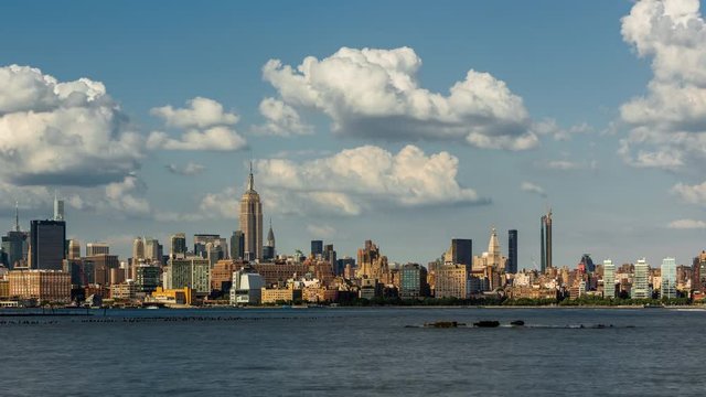 Cityscape time lapse of a summer afternoon in New York City, Manhattan. View of Midtown West skyscrapers, West Village and Hudson River with passing clouds