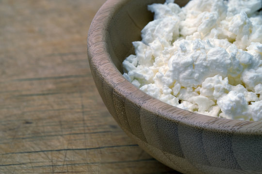 Cottage cheese in bowl on wooden table