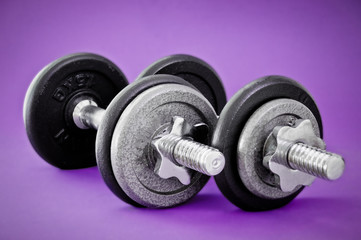 Naklejka na ściany i meble Closeup photo of two barbells on a purple background