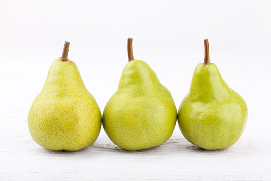 green pears on white wooden background..